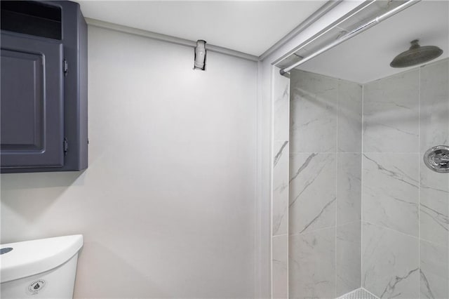 bathroom featuring tiled shower and toilet