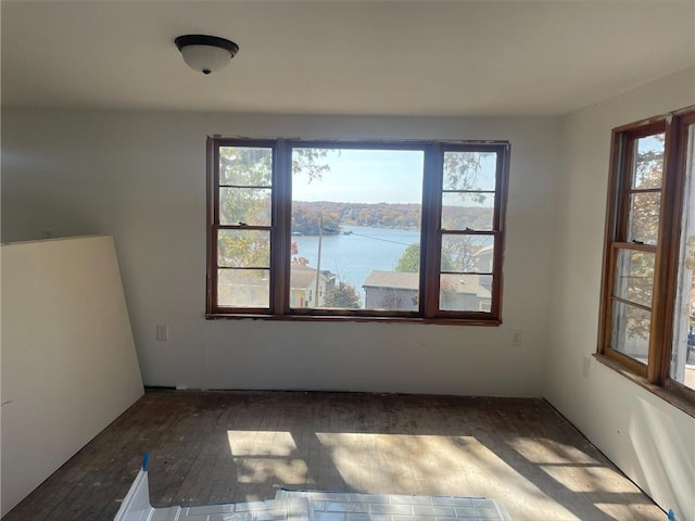 unfurnished room featuring dark wood-type flooring and a water view