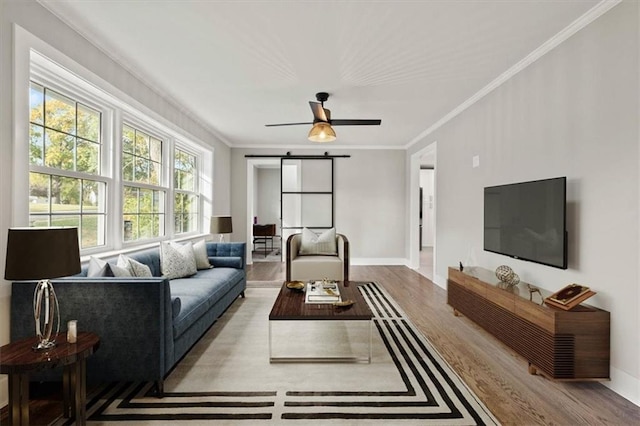 living room featuring crown molding, a barn door, light wood-type flooring, and a wealth of natural light