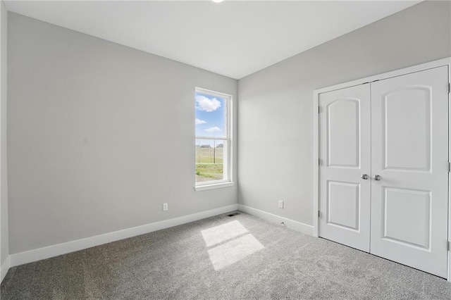 unfurnished bedroom with baseboards, carpet flooring, and a closet