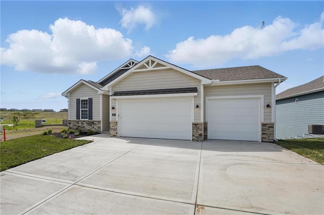 craftsman-style home with stone siding, an attached garage, cooling unit, and concrete driveway