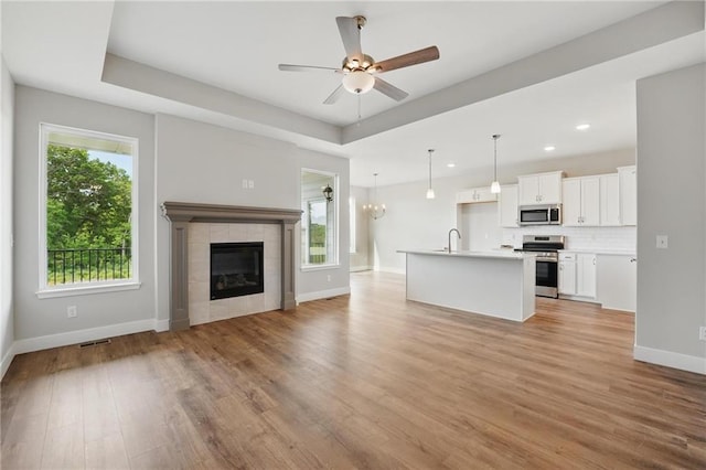 unfurnished living room with a sink, healthy amount of natural light, light wood-type flooring, baseboards, and recessed lighting