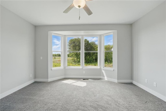 carpeted empty room featuring ceiling fan and baseboards