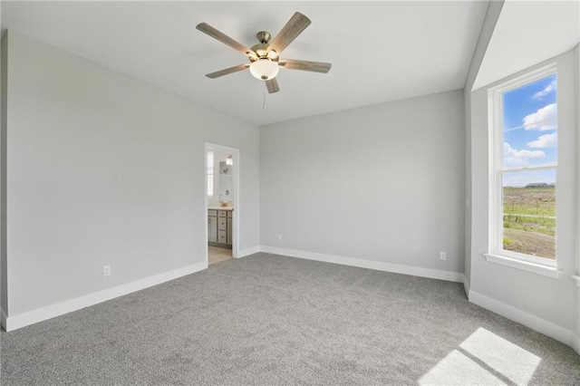 empty room with light colored carpet, a ceiling fan, and baseboards
