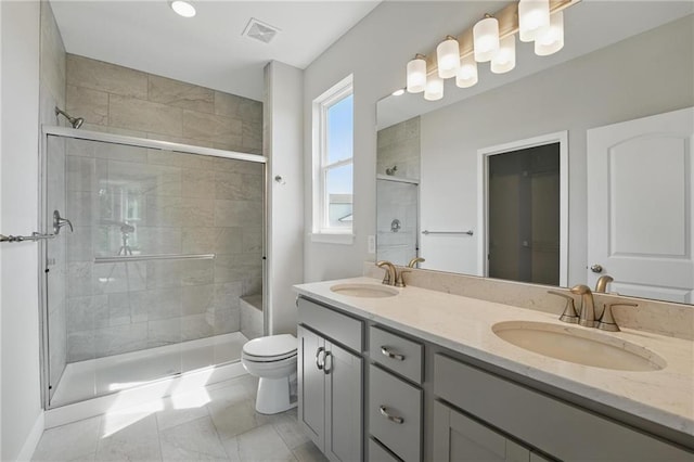 bathroom featuring a shower stall, toilet, and double vanity