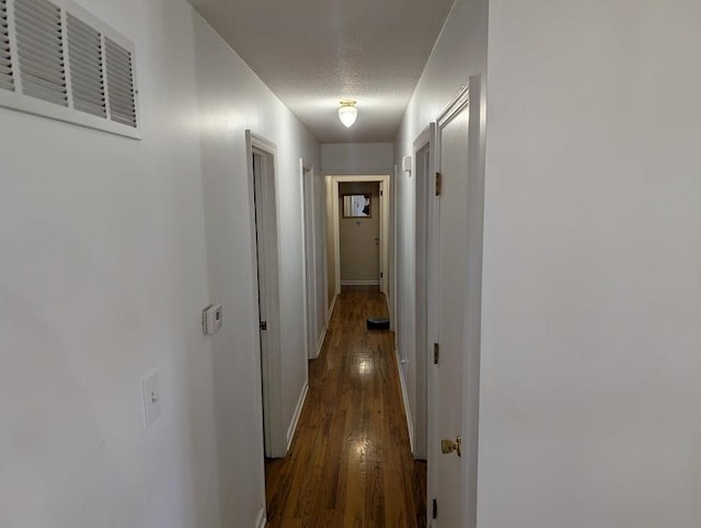 corridor with a textured ceiling and dark hardwood / wood-style floors