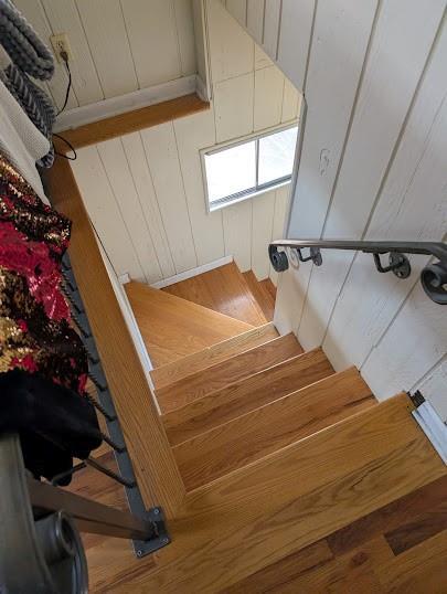 stairway with hardwood / wood-style flooring and wood walls