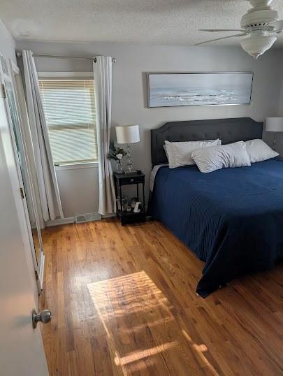 bedroom with ceiling fan, a textured ceiling, and hardwood / wood-style flooring