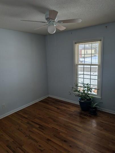 spare room featuring ceiling fan, a healthy amount of sunlight, dark hardwood / wood-style floors, and a textured ceiling