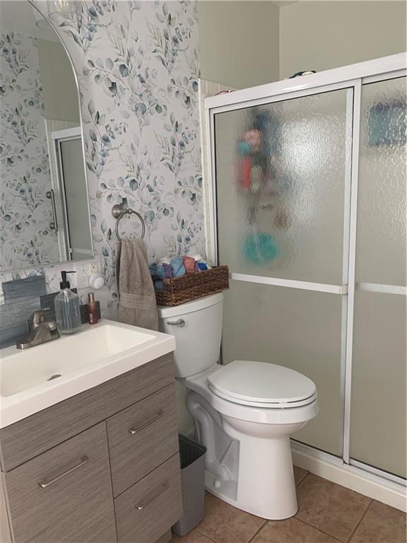 305 18th Ave N, Greenwood, MO 63034 - bathroom with toilet, tile patterned flooring, vanity, wallpapered walls, and a stall shower
