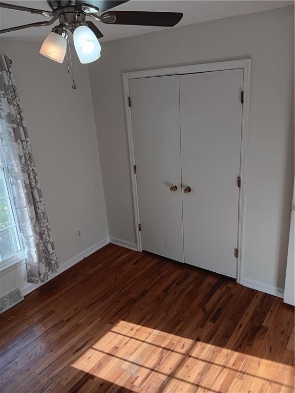 305 18th Ave N, Greenwood, MO 63034 - unfurnished bedroom featuring visible vents, baseboards, a ceiling fan, and wood finished floors