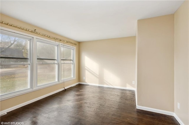 unfurnished room featuring a wealth of natural light and dark hardwood / wood-style floors