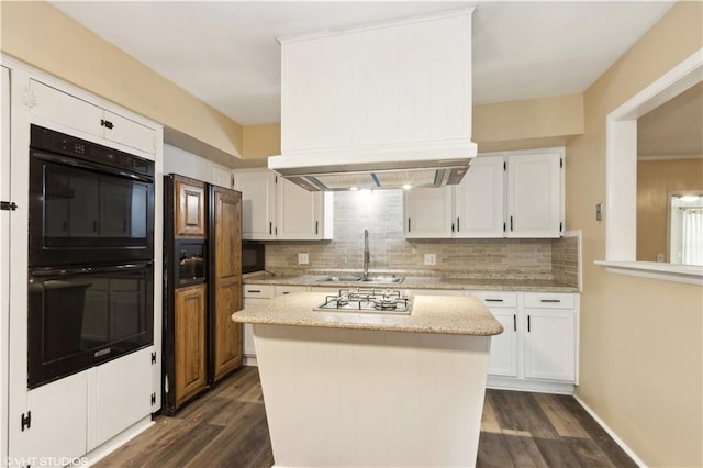 kitchen featuring dark hardwood / wood-style floors, black double oven, sink, white cabinets, and a center island