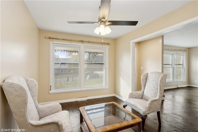 sitting room featuring dark wood-type flooring, a healthy amount of sunlight, and ceiling fan