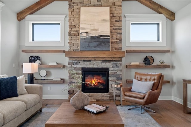 living room featuring a stone fireplace, lofted ceiling with beams, light hardwood / wood-style flooring, and plenty of natural light