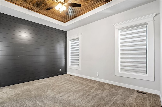 carpeted empty room featuring wood ceiling, a raised ceiling, and ceiling fan