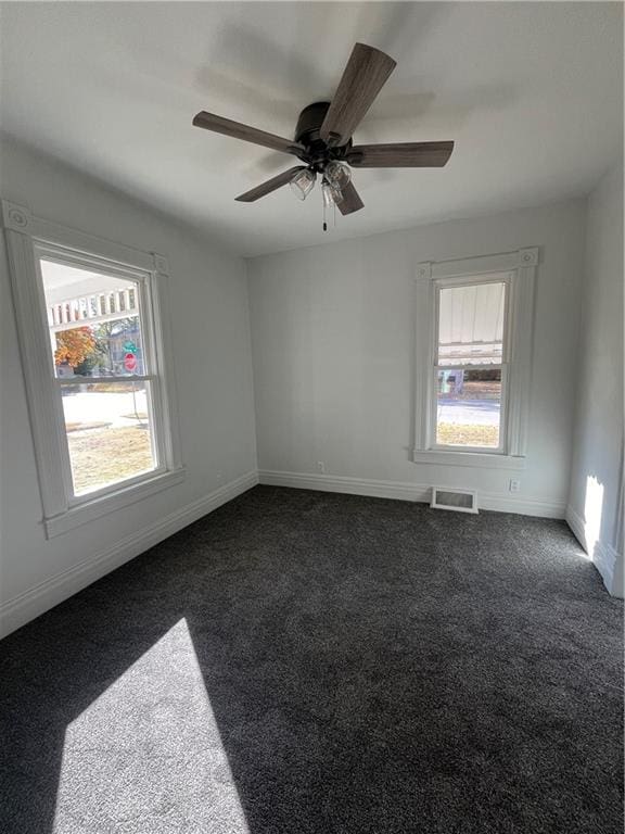 carpeted empty room with ceiling fan and plenty of natural light