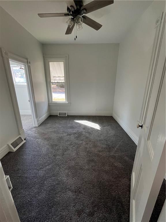 carpeted empty room with ceiling fan and plenty of natural light