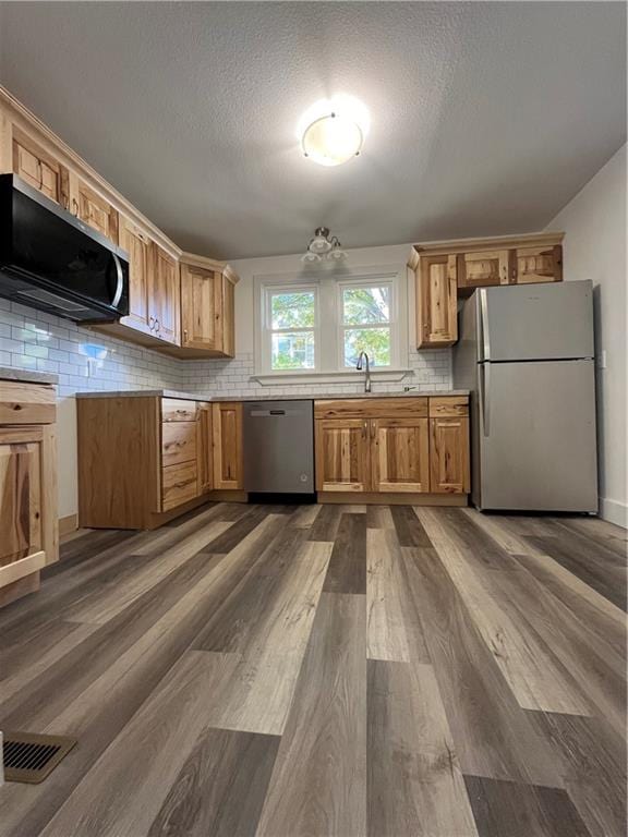 kitchen with backsplash, a textured ceiling, dark wood-type flooring, sink, and stainless steel appliances