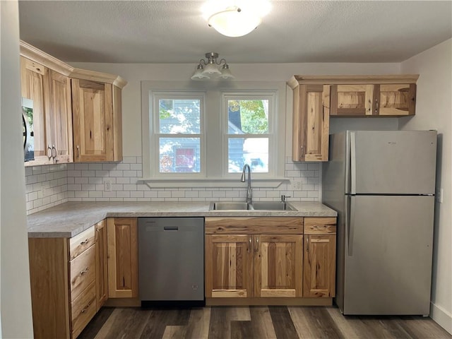 kitchen with appliances with stainless steel finishes, sink, dark wood-type flooring, and backsplash