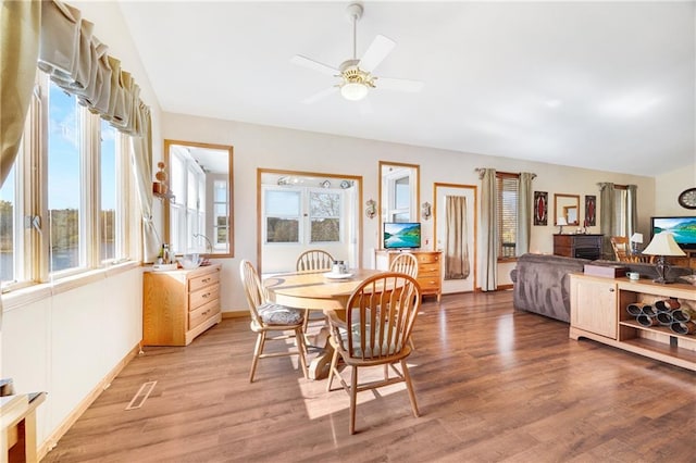 dining space with hardwood / wood-style flooring, ceiling fan, and vaulted ceiling