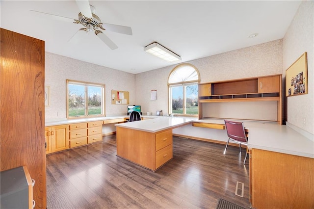 office area with ceiling fan, built in desk, and dark hardwood / wood-style flooring