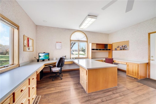 home office with built in desk, light hardwood / wood-style floors, and ceiling fan