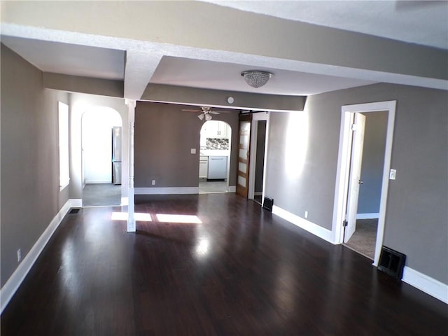 empty room with dark wood-type flooring, ornate columns, and ceiling fan