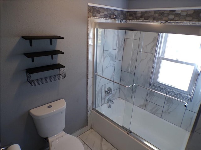 bathroom featuring combined bath / shower with glass door and toilet