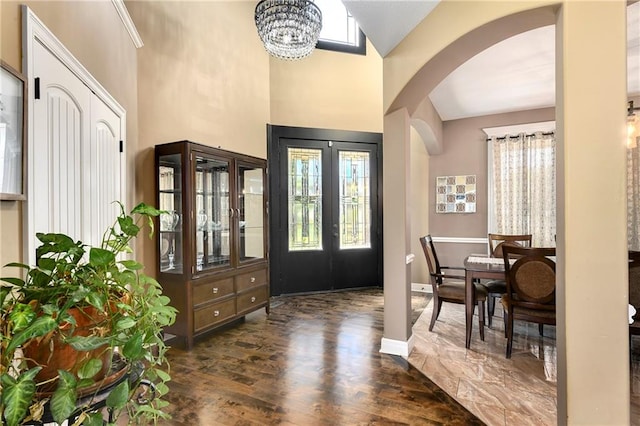 entryway with dark wood-type flooring, high vaulted ceiling, french doors, and a chandelier