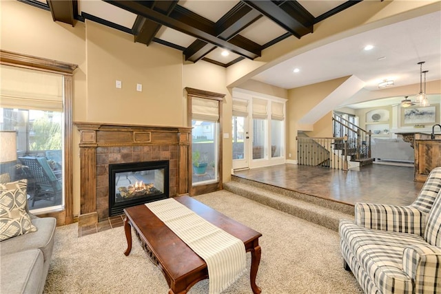 living room featuring a tiled fireplace, beam ceiling, a healthy amount of sunlight, and coffered ceiling