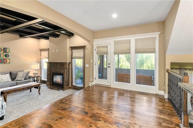 living room featuring dark hardwood / wood-style flooring, a tiled fireplace, and a wealth of natural light