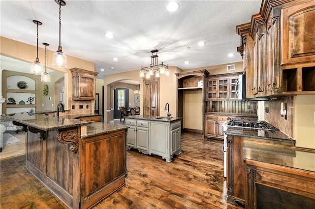 kitchen with a center island, dark stone counters, decorative light fixtures, and dark hardwood / wood-style flooring