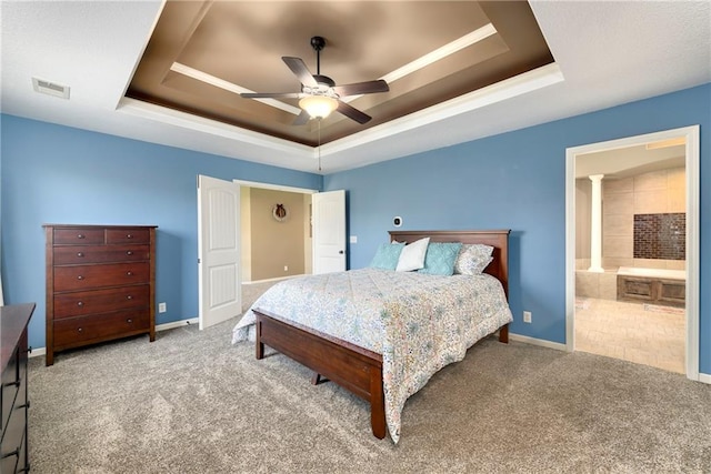 carpeted bedroom with ensuite bathroom, a tray ceiling, and ceiling fan