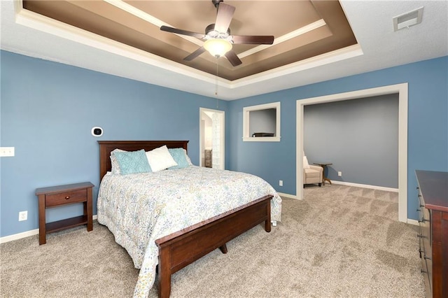 bedroom with ceiling fan, light carpet, and a tray ceiling