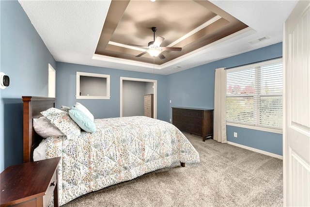 carpeted bedroom with ornamental molding, a tray ceiling, and ceiling fan