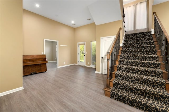 stairs featuring hardwood / wood-style floors and a high ceiling