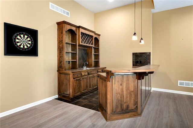 bar featuring sink, dark hardwood / wood-style floors, and hanging light fixtures