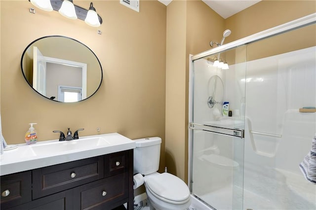 bathroom featuring a shower with door, vanity, and toilet