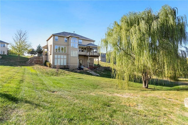 back of property featuring a balcony and a yard