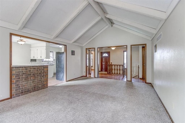 unfurnished living room with light carpet, beamed ceiling, and high vaulted ceiling