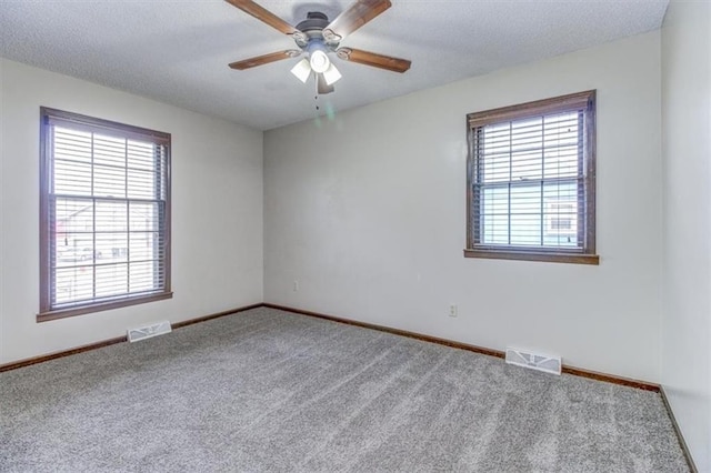 carpeted spare room with ceiling fan, a textured ceiling, and plenty of natural light