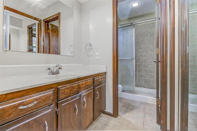 bathroom featuring toilet, an enclosed shower, vanity, and tile patterned floors