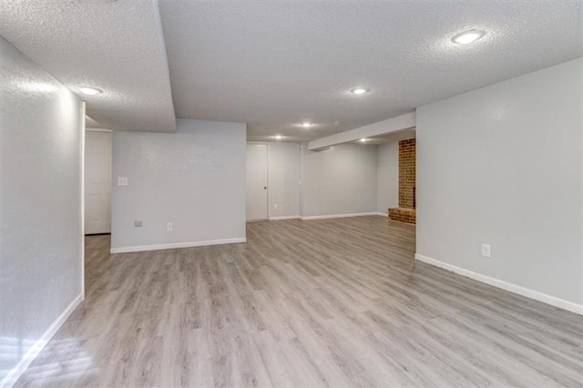 basement with light hardwood / wood-style flooring and a textured ceiling