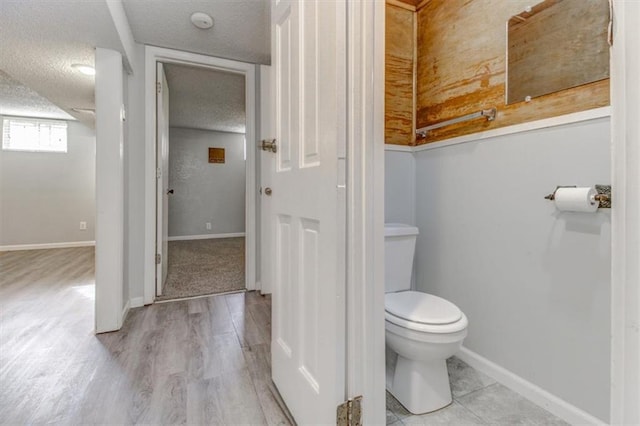 bathroom featuring toilet, hardwood / wood-style flooring, and a textured ceiling