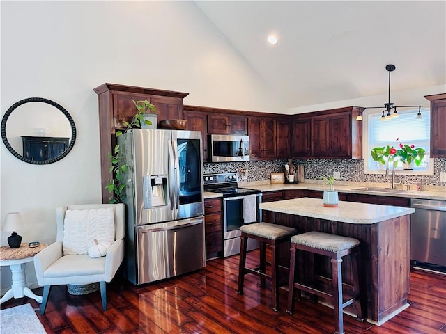 kitchen with stainless steel appliances, dark hardwood / wood-style flooring, a kitchen island, and hanging light fixtures