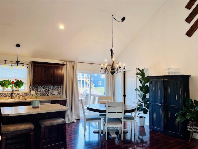 dining room with an inviting chandelier, high vaulted ceiling, sink, and dark hardwood / wood-style flooring