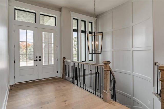 entryway with hardwood / wood-style floors, a chandelier, and french doors