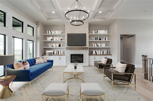 living room with a notable chandelier, coffered ceiling, a fireplace, beamed ceiling, and light wood-type flooring