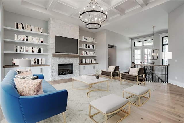 living room with a chandelier, coffered ceiling, beam ceiling, a fireplace, and light hardwood / wood-style flooring